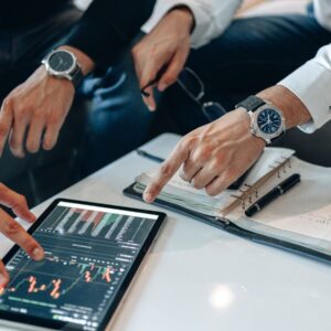 Two businessmen discussing financial data on a tablet during a meeting.