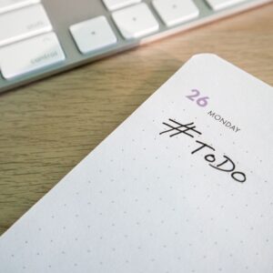 Close-up of a to-do list next to a computer keyboard on a desk.