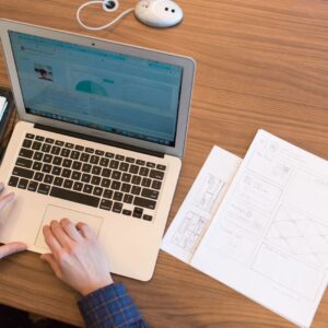 An overhead view of a person working on a laptop at a desk with documents and papers.