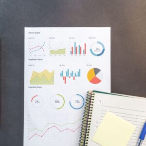 Top-down view of a desk with charts, a laptop, and notebooks, ideal for data analysis themes.