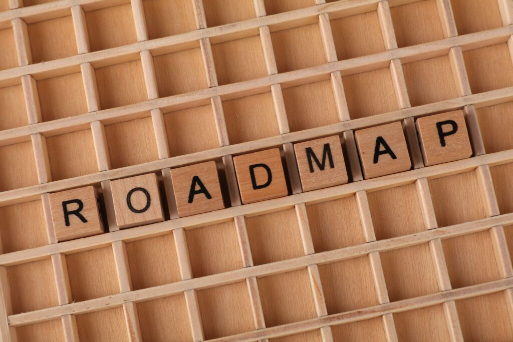 Wooden letter blocks spelling ROADMAP on a square grid layout, top view.