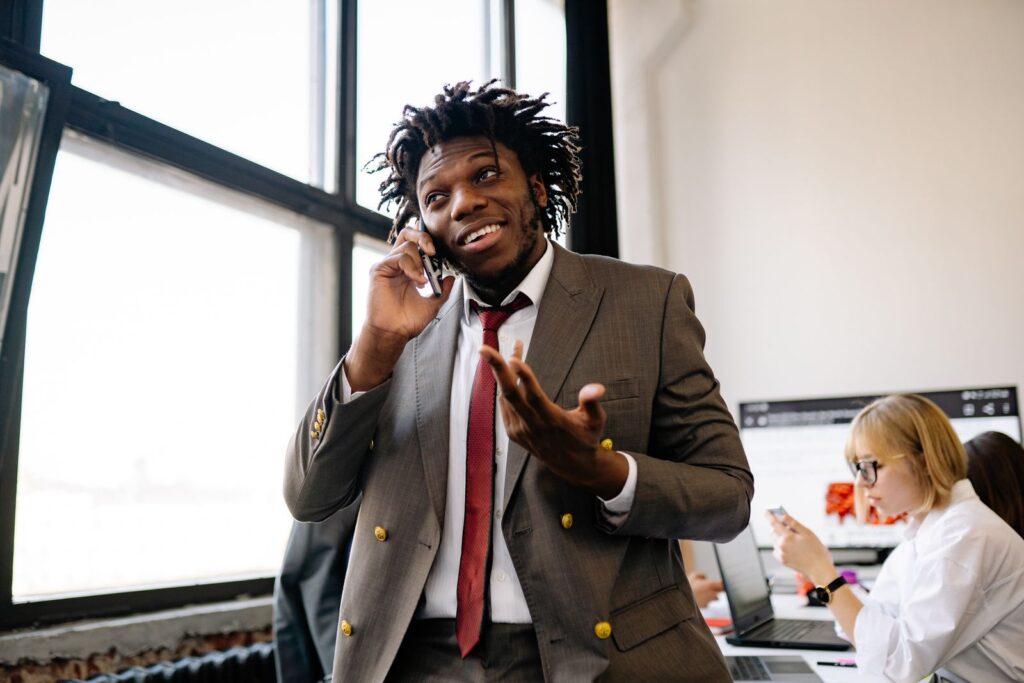 Professional businessman smiling while talking on the phone in an office setting.