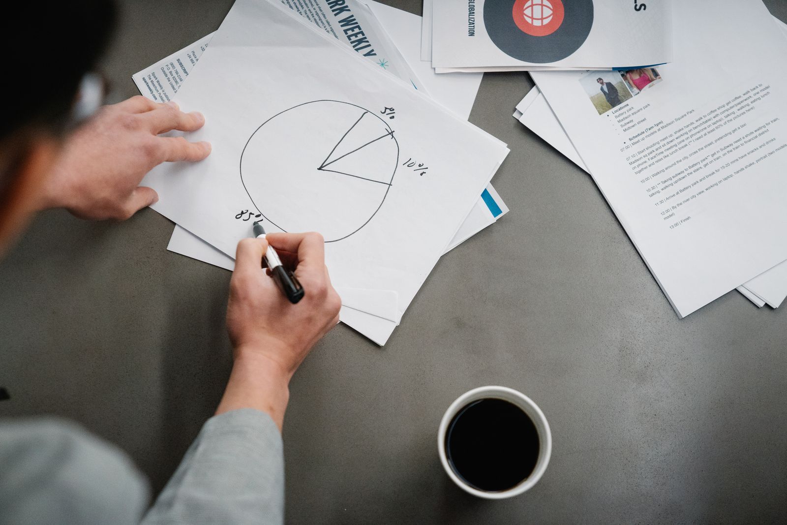 Man drawing a pie chart on paper with coffee, representing business planning and analysis.